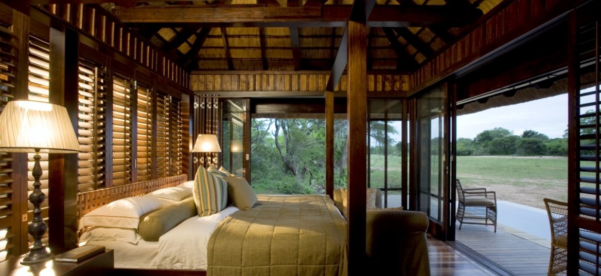 Double bed in room with a view on the outside deck and landscape.